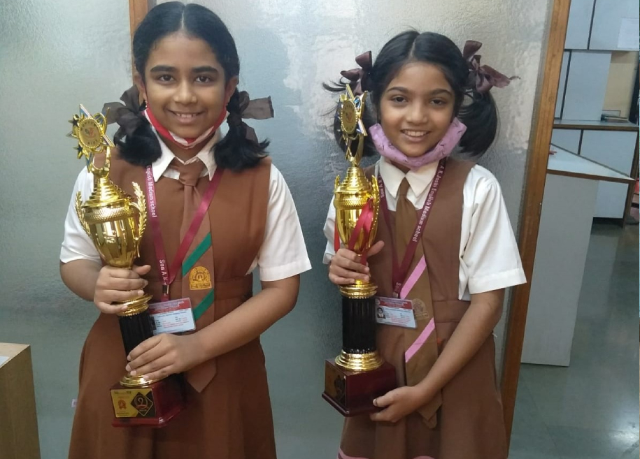 Students proudly displaying their awards and certificates for their outstanding achievements in various competitions and examinations at AK Joshi CBSE School in Thane, representing excellence and success.